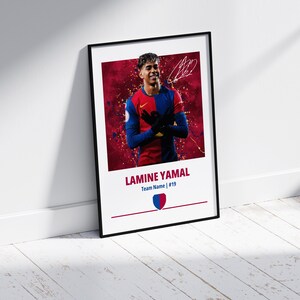 May include: A framed poster featuring a soccer player in a red and blue jersey with a red background. The player is holding his hands together in front of him. The poster includes the player's name, "LAMINE YAMAL", and the team name and number, "Team Name | #19".
