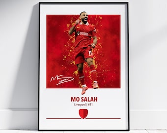 May include: A red and white poster featuring a soccer player in a red jersey with a white and gold design. The player is jumping in the air with his arms raised. The poster has a red background with yellow paint splatters. The player's signature is in the bottom left corner. The text "MO SALAH" is in the bottom center of the poster. The text "Liverpool | #11" is below the player's name. A red shield with a white outline is below the text.