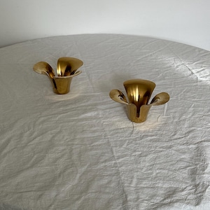 May include: Two gold metal candle holders shaped like flowers with five petals each.