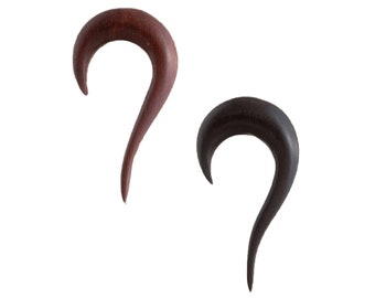 May include: Two curved ear tapers made of wood, one in a reddish-brown tone and the other in a dark black tone. Each piece features a smooth, polished finish with a tapered point at the bottom and a wider, rounded top section for ear stretching.