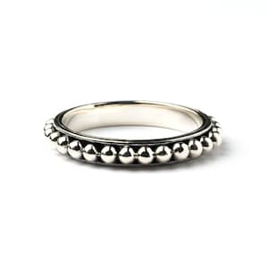 May include: A silver ring with a beaded edge. The ring is simple and elegant.