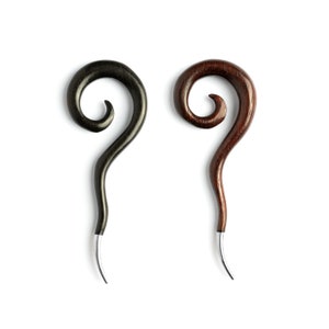 May include: Two wooden ear gauges with a spiral design. One is black and the other is brown.