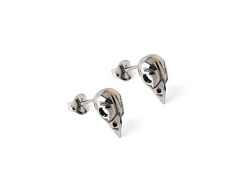 May include: A pair of silver skull stud earrings. The skulls are detailed and have a hollowed-out look.