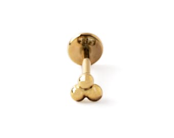 May include: Gold body jewelry with a three-ball design. The jewelry is a stud earring with a flat back.