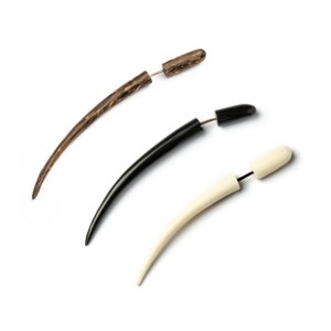 May include: Three wooden ear gauges, one brown, one black, and one white. Each gauge is a curved shape with a metal pin.