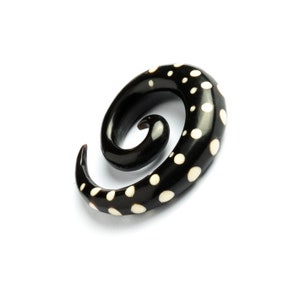 May include: Black and white spiral ear gauge with a polka dot pattern.