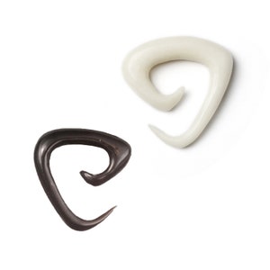 May include: Two spiral ear gauges, one black and one white. The gauges are made of a smooth, shiny material and have a unique, curved design.