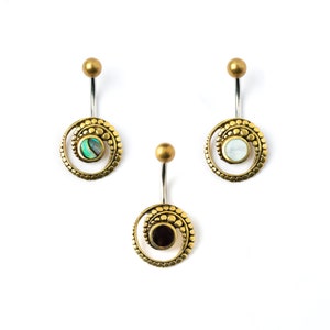Puede incluir: Tres anillos de ombligo dorados con piedras de colores diferentes. Los anillos tienen un diseño en espiral y están hechos de metal.