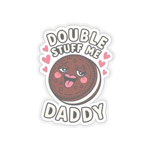 May include: A sticker featuring a cartoon cookie with a face, tongue sticking out, and pink cheeks. The text reads "DOUBLE STUFF ME DADDY" in a playful font, with pink hearts around the cookie.