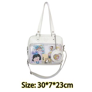 Puede incluir: Bolso tote blanco transparente de pl&aacute;stico con ribete de cuero blanco y dise&ntilde;o en forma de coraz&oacute;n. El bolso tiene un asa superior y una correa para el hombro. El bolso est&aacute; lleno de peque&ntilde;as pegatinas y pines de personajes de dibujos animados. Tama&ntilde;o: 30*7*23cm.