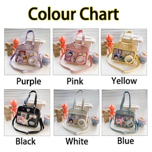 Puede incluir: Una tabla de colores que muestra diferentes bolsos de pl&aacute;stico transparente de colores con una ventana transparente y un dije en forma de coraz&oacute;n. Los colores son morado, rosa, amarillo, negro, blanco y azul.