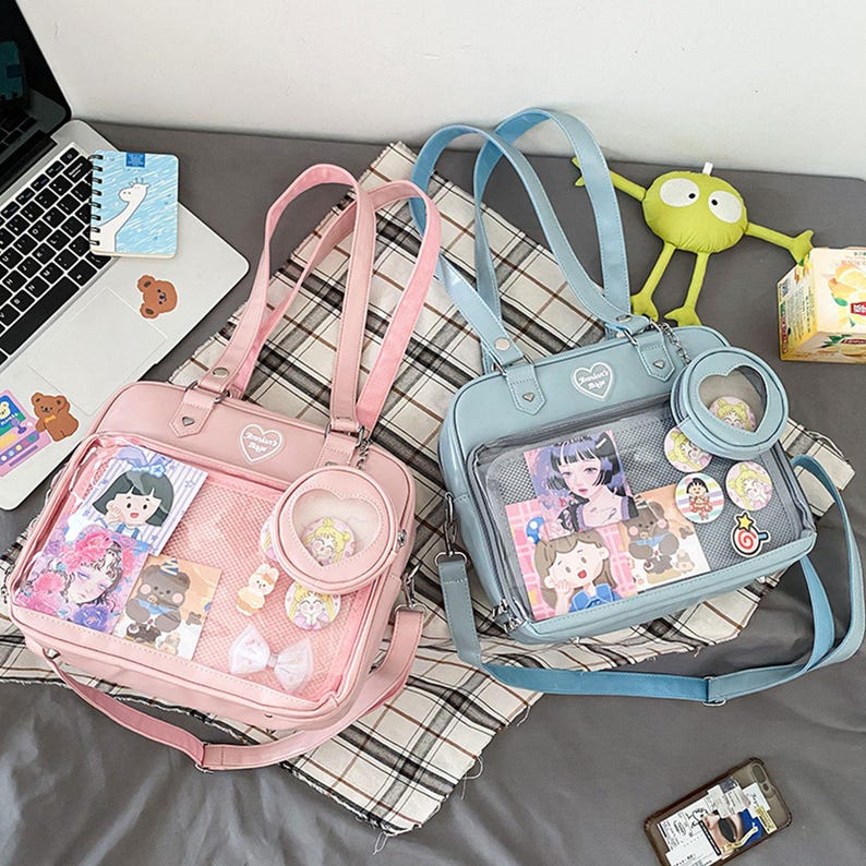 Puede incluir: Dos mochilas de pl&aacute;stico transparente con correas ajustables. Una mochila es rosa con un dise&ntilde;o de coraz&oacute;n y la otra es azul con un dise&ntilde;o de estrella. Ambas mochilas tienen personajes de dibujos animados e im&aacute;genes en su interior.