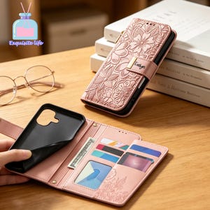 May include: A light pink wallet-style phone case featuring an embossed floral pattern and a magnetic closure tab with the name Evelyn printed on it. The interior includes a black phone holder, multiple card slots, and a clear ID window.