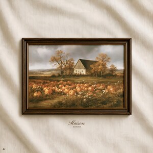 May include: A rectangular landscape painting in a dark brown frame depicting a field of orange pumpkins in front of a barn under a cloudy sky. The text "la Maison AURORA" is printed in small black letters below the frame on the off-white fabric.