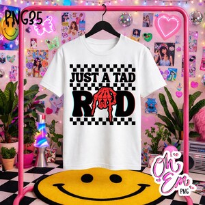 Może przedstawiać: Biały t-shirt z krótkim rękawem i czarno-białym wzorem w szachownicę w tle. Z przodu znajduje się napis JUST A TAD RAD, w którym czerwona szkieletowa dłoń zastępuje literę A w słowie RAD.