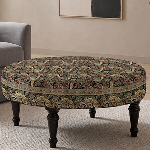 May include: A round ottoman featuring a dark fabric upholstery with a dense, multi-colored floral and paisley pattern. The piece is supported by four dark brown, turned wooden legs that provide a stable base for the circular, cushioned top.