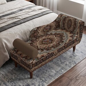 May include: A chaise lounge featuring a detailed, multi-colored floral and geometric pattern in shades of brown, cream, and blue. The furniture piece includes a solid brown cylindrical bolster pillow and is supported by four dark wooden legs.