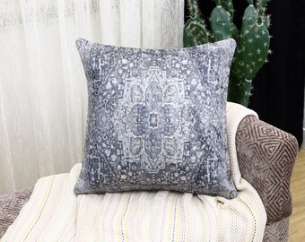 May include: A decorative throw pillow with a gray and white patterned design. The pillow is sitting on a white and yellow striped throw blanket.