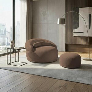 May include: A brown, corduroy-textured armchair with a matching ottoman and a small side table. The chair has a curved back and a cylindrical pillow. A silver arc lamp and a cityscape are visible in the background.