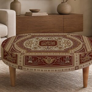 May include: A round ottoman featuring a deep red and cream patterned fabric with intricate floral and geometric motifs. The piece is supported by four light-toned wooden legs, providing a stable base for this low-profile furniture item.