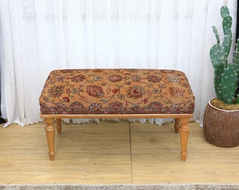Taburete otomano rectangular con tapizado floral denso en tonos cálidos de naranja, marrón, rojo y verde. Taburete de estilo vintage. Banco con acento bohemio.