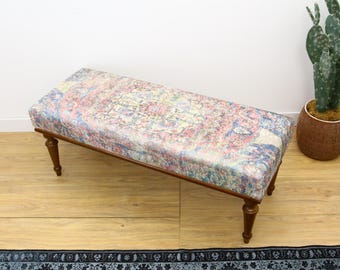 Puede incluir: Un banco de madera con un asiento de tela estampada de colores. La tela tiene un diseño floral y geométrico en tonos de rosa, azul y amarillo.
