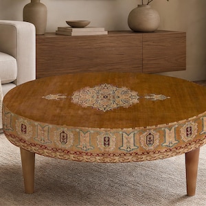 May include: A round wooden coffee table featuring a warm brown finish and a decorative central medallion pattern. The side of the table is adorned with a repeating intricate border design in shades of blue, cream, and red, supported by four legs.