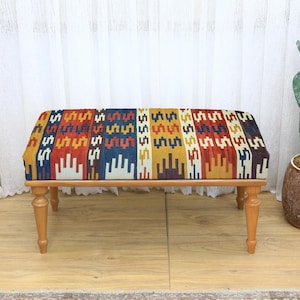 Rechteckiger Ottomane mit geometrischer Schwarz-Weiß-Polsterung, die auf Holzbeinen steht, modernes Akzentstück für stilvolle Innenräume, gemütlicher Sitz