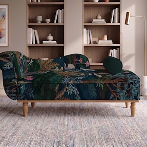 May include: A chaise lounge featuring a dark blue fabric upholstery with a vibrant botanical print of tropical leaves, flowers, and birds. The furniture piece has a curved backrest, a cylindrical bolster pillow, and four light-colored wooden legs.