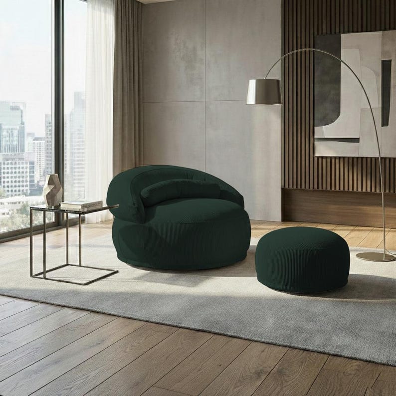 Pu&ograve; includere: Una poltrona moderna verde scuro con un pouf abbinato. La sedia ha uno schienale arrotondato e un piccolo cuscino attaccato. Il pouf &egrave; circolare. L'arredamento &egrave; in una stanza con una grande finestra, un tavolino e una lampada da terra.
