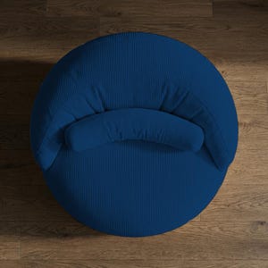 May include: A top-down view of a navy blue corduroy armchair. The chair has a rounded shape with a curved back and a small, cushioned armrest. The corduroy fabric has a vertical ribbed texture.