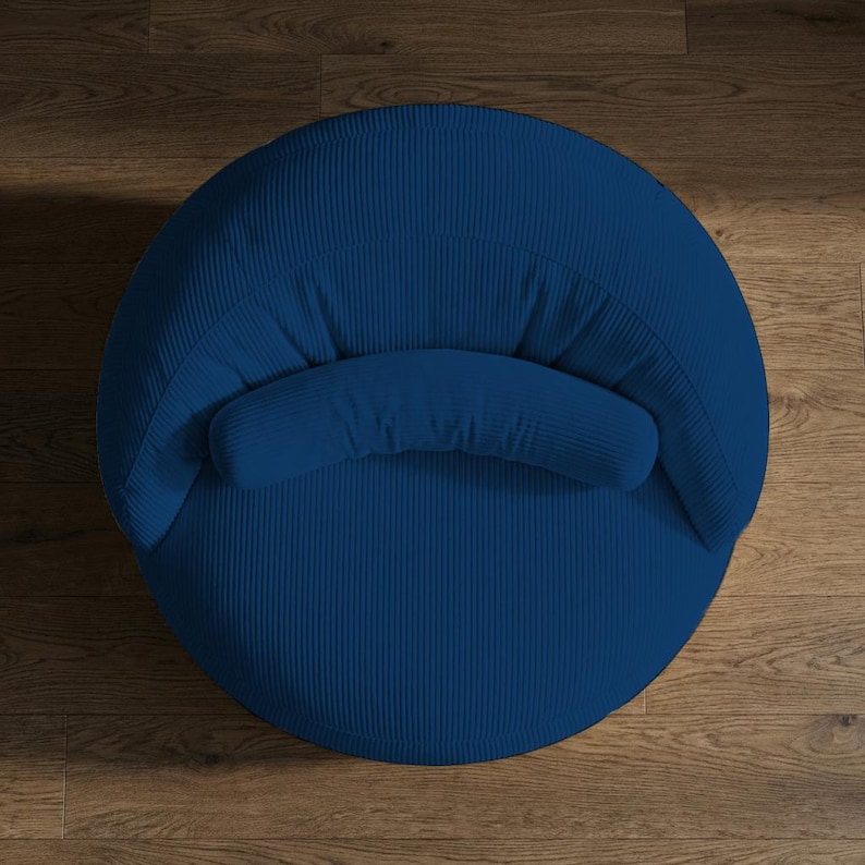 May include: A top-down view of a navy blue corduroy armchair. The chair has a rounded shape with a curved back and a small, cushioned armrest. The corduroy fabric has a vertical ribbed texture.