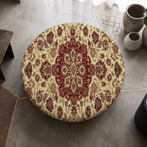 May include: A circular rug featuring a detailed, symmetrical floral pattern in shades of deep red, cream, and dark brown. The intricate design radiates from a central medallion, covering the entire surface of the round textile piece.