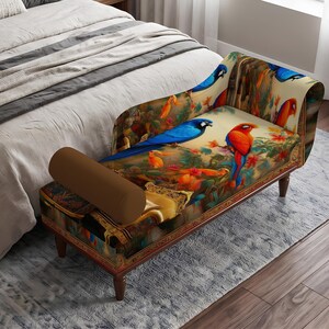 May include: A chaise lounge featuring a vibrant, multi-colored print of tropical parrots and lush foliage. The piece includes a solid brown cylindrical bolster pillow, a curved backrest, and dark wooden legs, positioned at the foot of a bed.