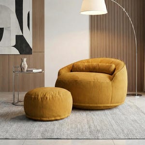 May include: A mustard yellow corduroy armchair with a matching ottoman. The chair has a rounded shape with a bolster pillow. The ottoman is circular. The furniture sits on a gray rug.