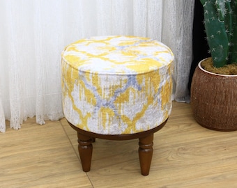 Könnte beinhalten: Ein runder, gelber und grauer Hocker mit Holzbeinen. Der Hocker steht auf einem Holzboden.