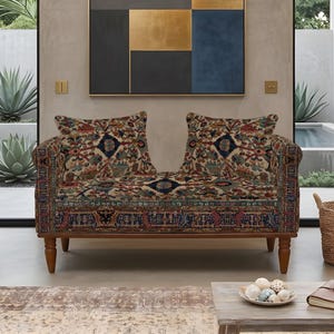 May include: A loveseat featuring a multi-colored, intricate traditional rug-style pattern in shades of red, blue, and cream. The piece has a wooden frame with four tapered legs and two matching square throw pillows upholstered in the same fabric.