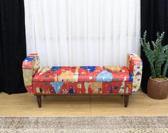 May include: A decorative bench with a colorful, abstract pattern in red, blue, and yellow. The bench has a wooden frame and legs. The arms of the bench are curved and upholstered with the same patterned fabric.