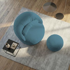 May include: A teal blue, round accent chair with a matching ottoman. The chair has a curved back and a small, attached pillow. The ottoman is a smaller, solid sphere. The furniture sits on a light gray rug.