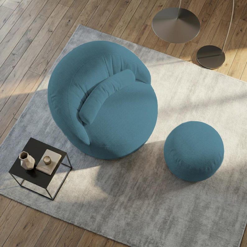 May include: A teal blue, round accent chair with a matching ottoman. The chair has a curved back and a small, attached pillow. The ottoman is a smaller, solid sphere. The furniture sits on a light gray rug.