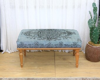 May include: A rectangular ottoman with a light blue and gray patterned top and four wooden legs. The fabric features a detailed floral design. The ottoman is a decorative furniture piece.