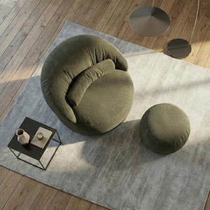 Pode incluir: Uma poltrona de veludo cotel&ecirc; verde-oliva com um pufe a condizer sobre um tapete cinza claro. Uma pequena mesa lateral preta com objetos decorativos est&aacute; em primeiro plano. A cadeira tem uma forma arredondada e um encosto curvo.