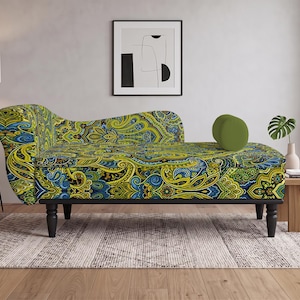 May include: A chaise lounge featuring a vibrant paisley pattern in shades of lime green, blue, and black. The furniture piece has a curved backrest, a single solid olive green cylindrical bolster pillow, and four dark, turned wooden legs.