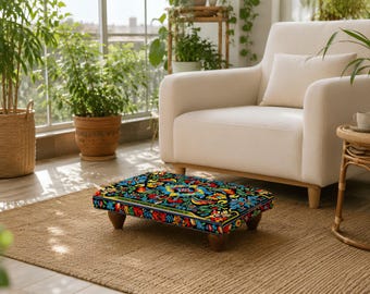 May include: A rectangular footstool featuring a vibrant, multi-colored floral pattern on a black background. The design includes intricate red, blue, yellow, and green botanical motifs. The footstool is supported by four short, dark brown wooden legs.