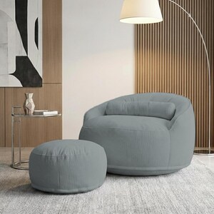 Pode incluir: Uma poltrona beanbag de veludo cotel&ecirc; cinza claro com um pufe a condizer. A cadeira tem encosto arredondado e uma almofada cil&iacute;ndrica. O pufe &eacute; circular. Uma moderna lumin&aacute;ria de ch&atilde;o e uma mesa lateral est&atilde;o no fundo.