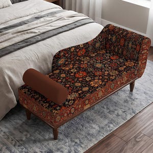 May include: A chaise lounge featuring a dark fabric upholstery with a multi-colored floral and geometric pattern. The piece includes a solid brown cylindrical bolster pillow, a single raised armrest, and four dark wooden legs for support.