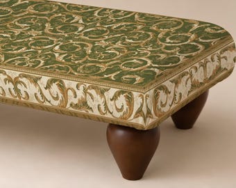May include: A rectangular ottoman featuring a dark green top surface with a repeating gold and cream acanthus leaf scroll pattern. The sides are upholstered in a cream fabric with a matching gold and green scroll design, supported by dark brown legs.