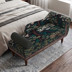 May include: A chaise lounge featuring a dark fabric upholstery with a dense botanical pattern of deep green leaves, brown tree branches, and white flowers. The piece has a single bolster pillow, a curved backrest, and four dark wooden legs.