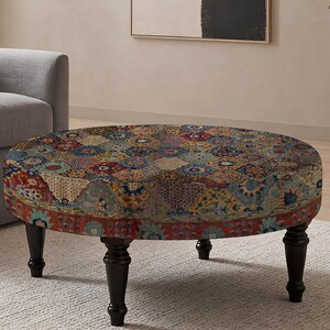 May include: A round ottoman featuring a multi-colored patchwork pattern with intricate floral and geometric motifs in shades of red, blue, yellow, and cream. The piece is supported by four dark brown, turned wooden legs that provide a stable base.