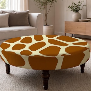 May include: A round ottoman featuring a cream-colored base with a brown giraffe-inspired spot pattern. The piece is supported by four dark brown, turned wooden legs that provide a stable base for the circular, upholstered top surface.